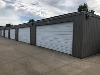 a row of three car garages with a cloudy sky in the background